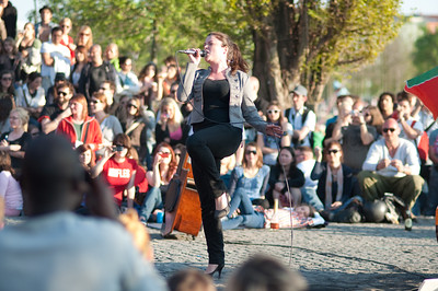 person singing into microphone to a crowd in a park