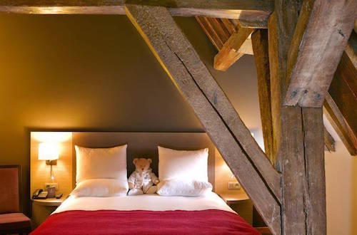 red bed under wood ceiling beam at Martins Brugge, one of the best budget hotels in bruges